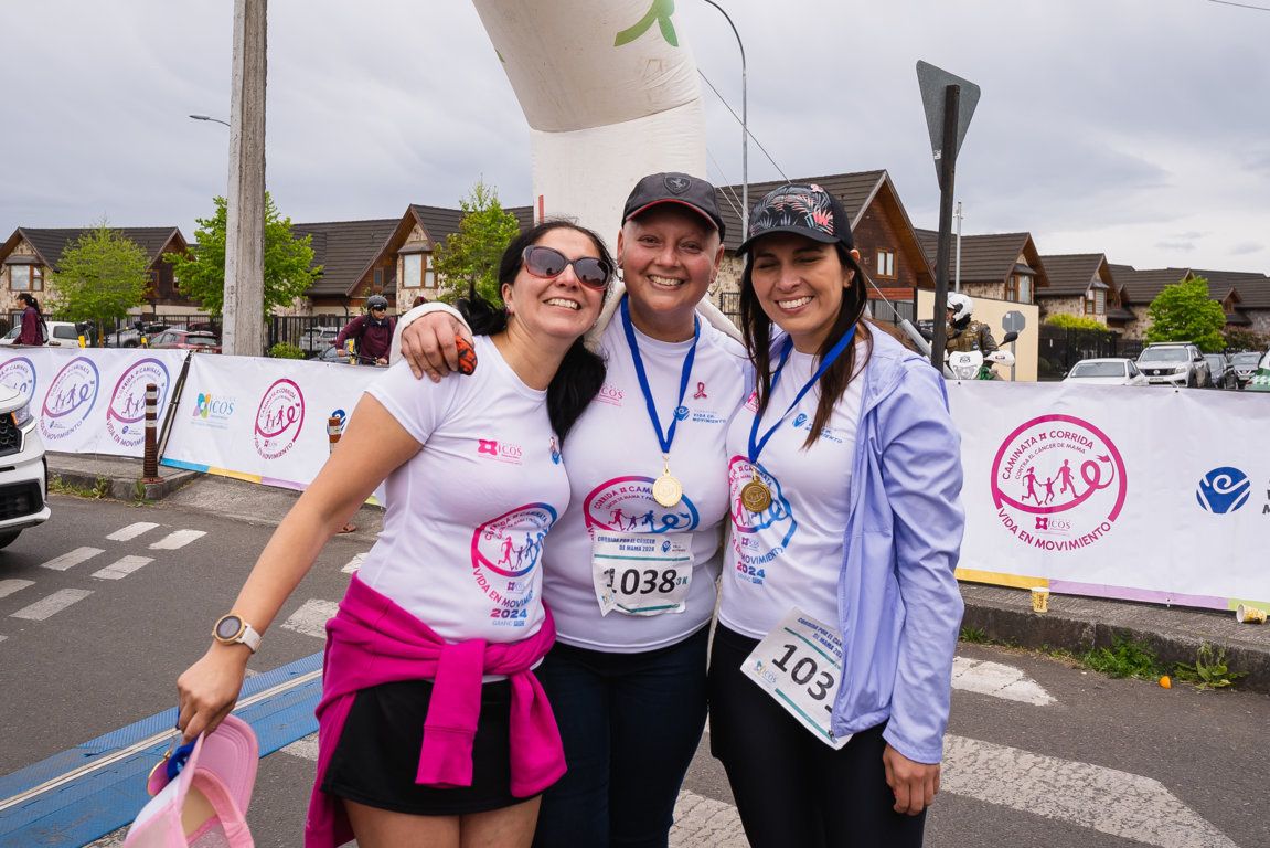 Tres participantes con medallas junto al arco de meta · edición 2024