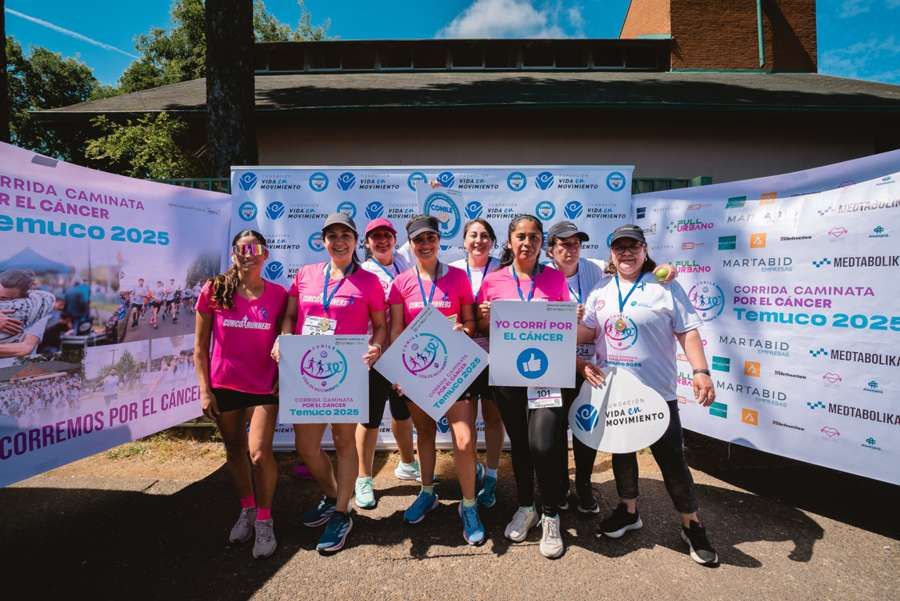 Grupo con carteles “Yo corrí por el cáncer” · edición 2025